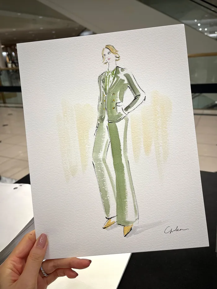 Hand holding fashion illustration of a woman in green suit