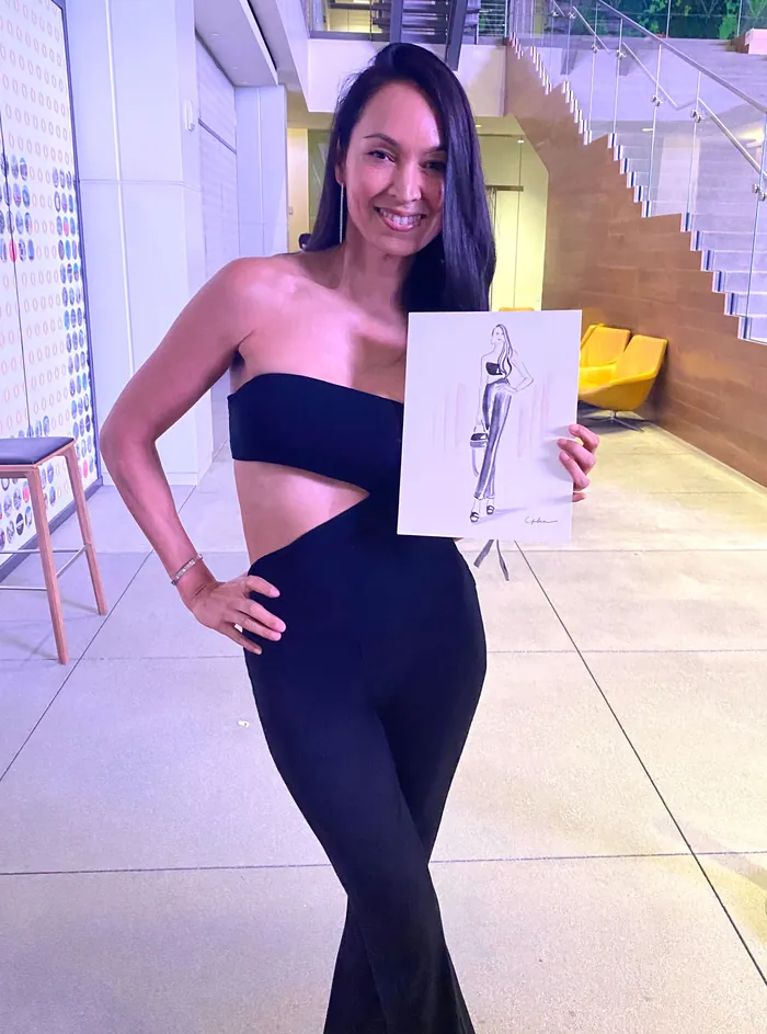 Woman in black outfit holding fashion sketch at LA Fashion Week