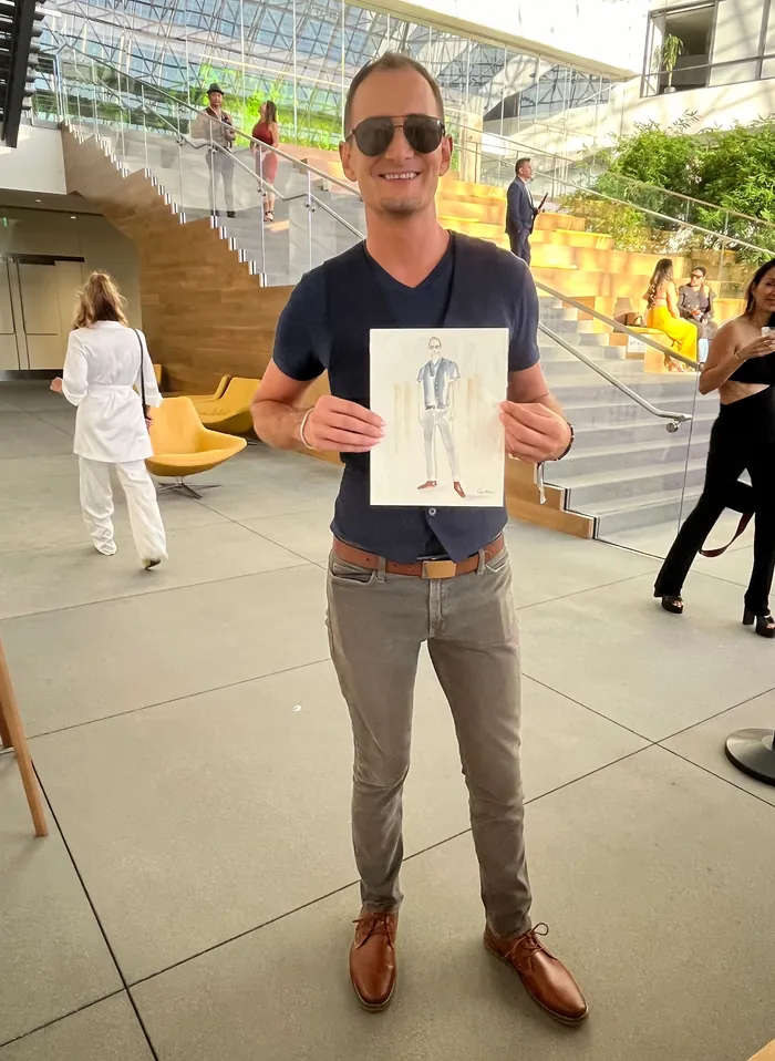 Man holding fashion sketch at outdoor LA Fashion Week event