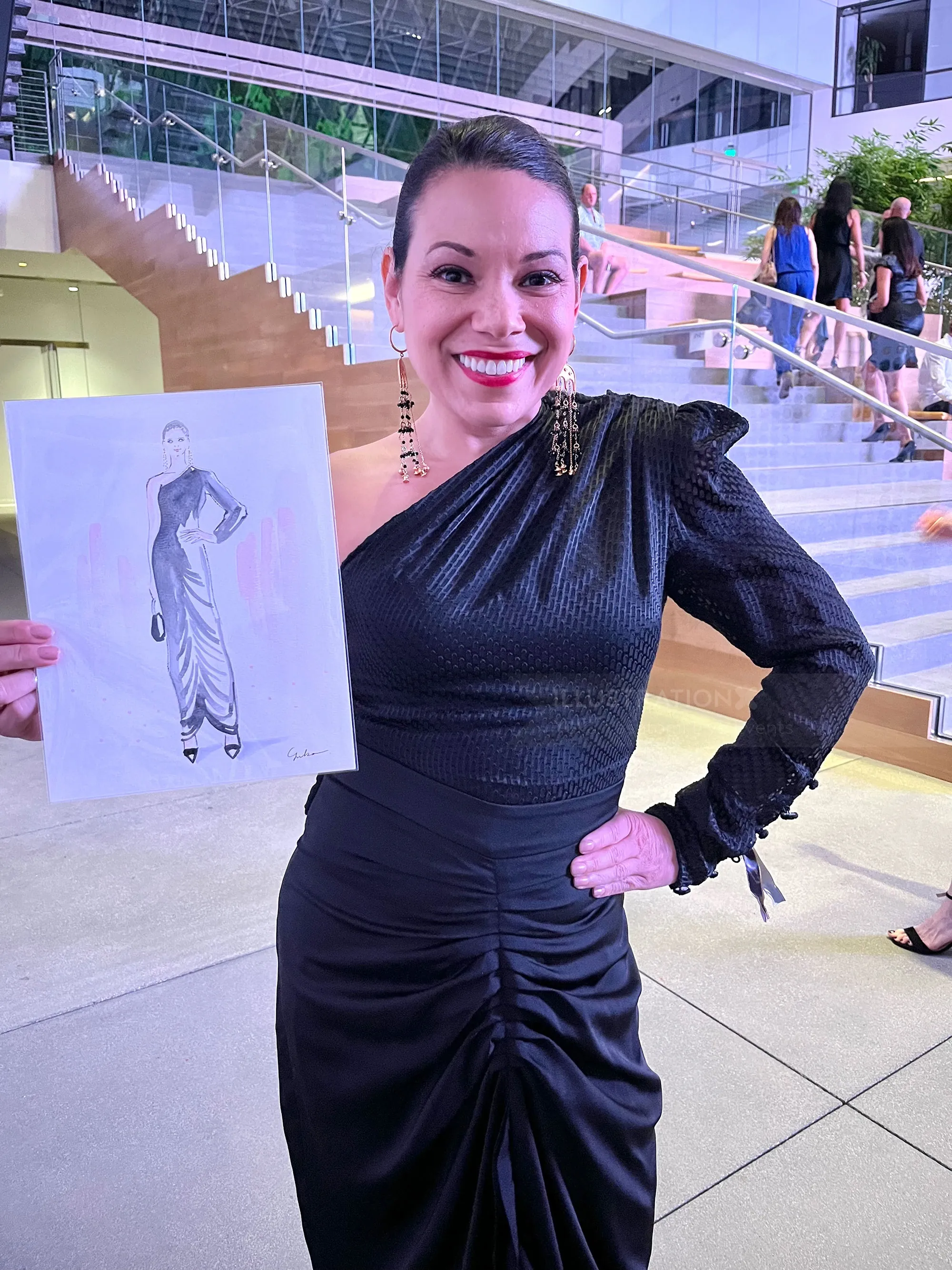 Woman in black dress holding fashion sketch at LA Fashion Week