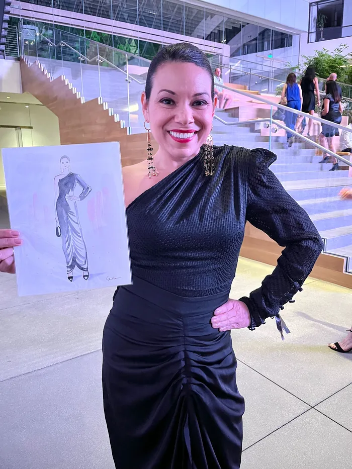 Woman in black dress holding fashion sketch at LA Fashion Week