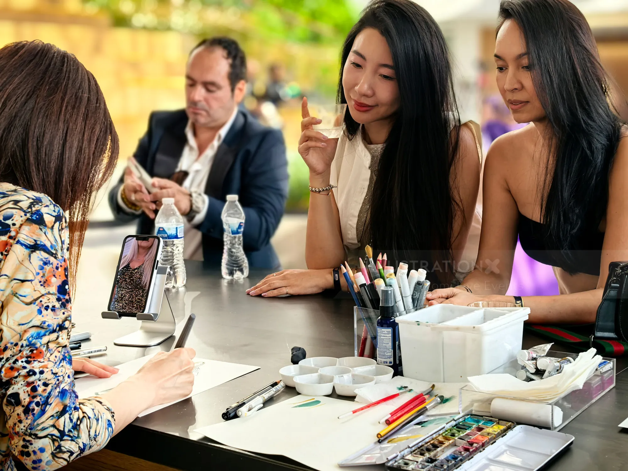 Two women watching artist sketch at an outdoor event