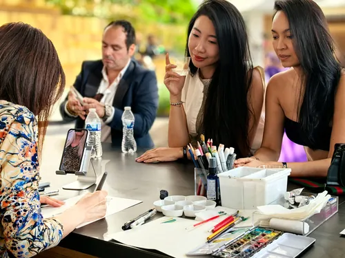 Two women watching artist sketch at an outdoor event