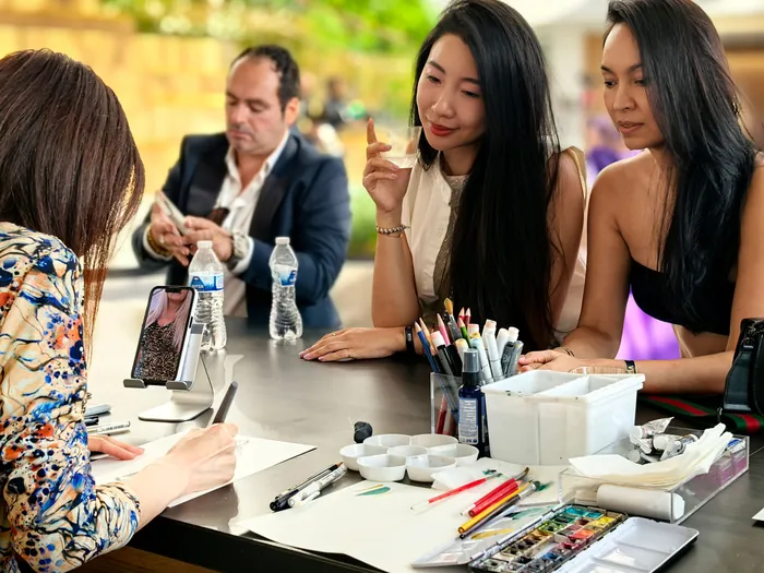 Two women watching artist sketch at an outdoor event