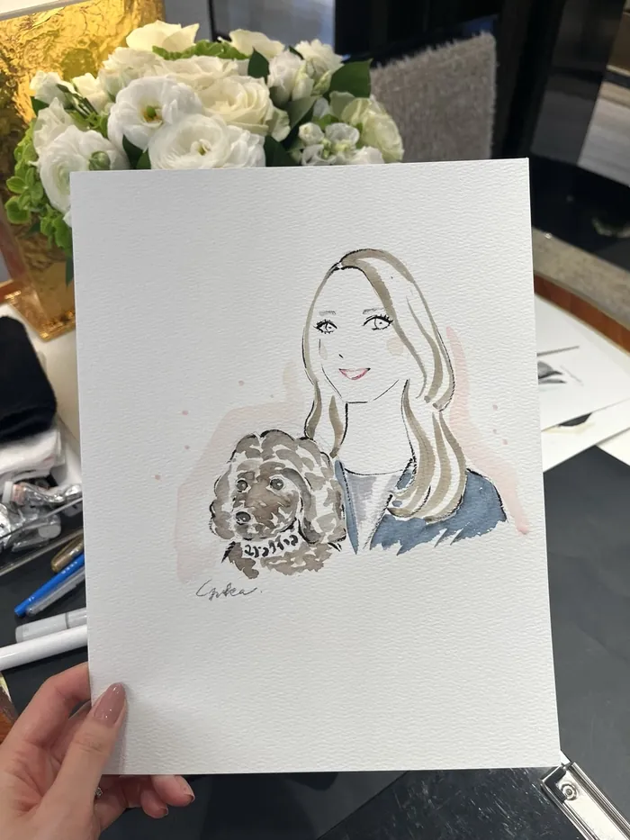 Hand holding a watercolor portrait of woman with dog
