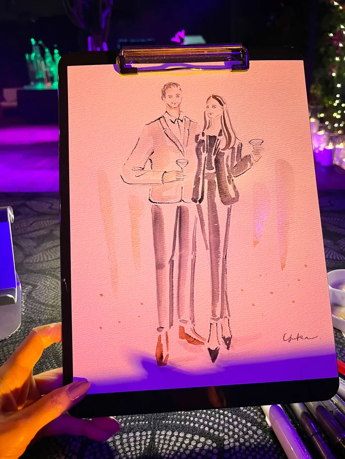 Hand holding caricature drawing of a couple at a party