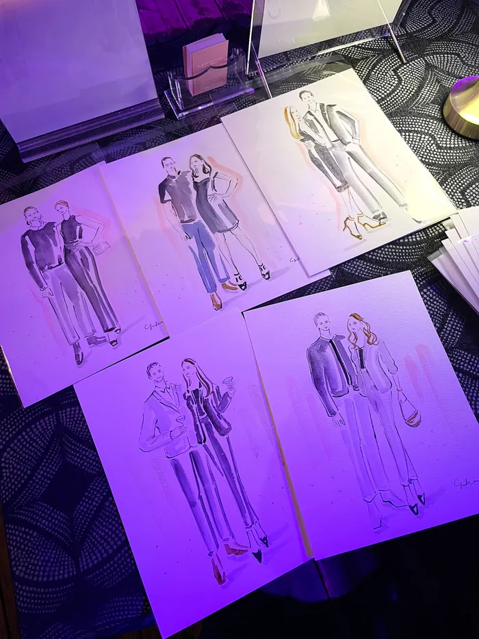 Fashion sketches of male and female models on table under purple light