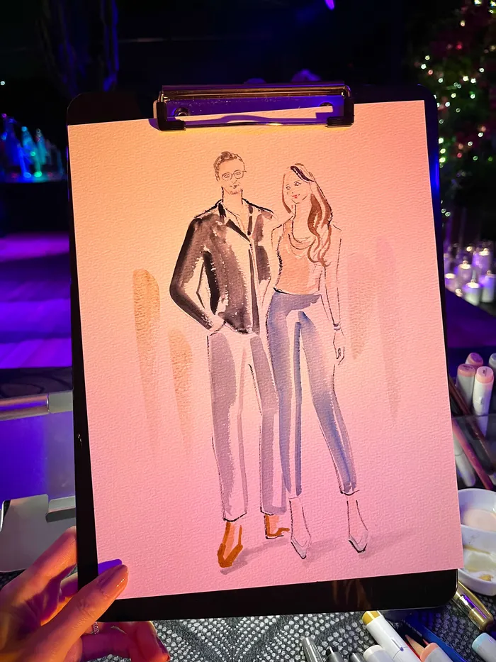 Hand holding a clipboard with a fashion illustration of a man and woman