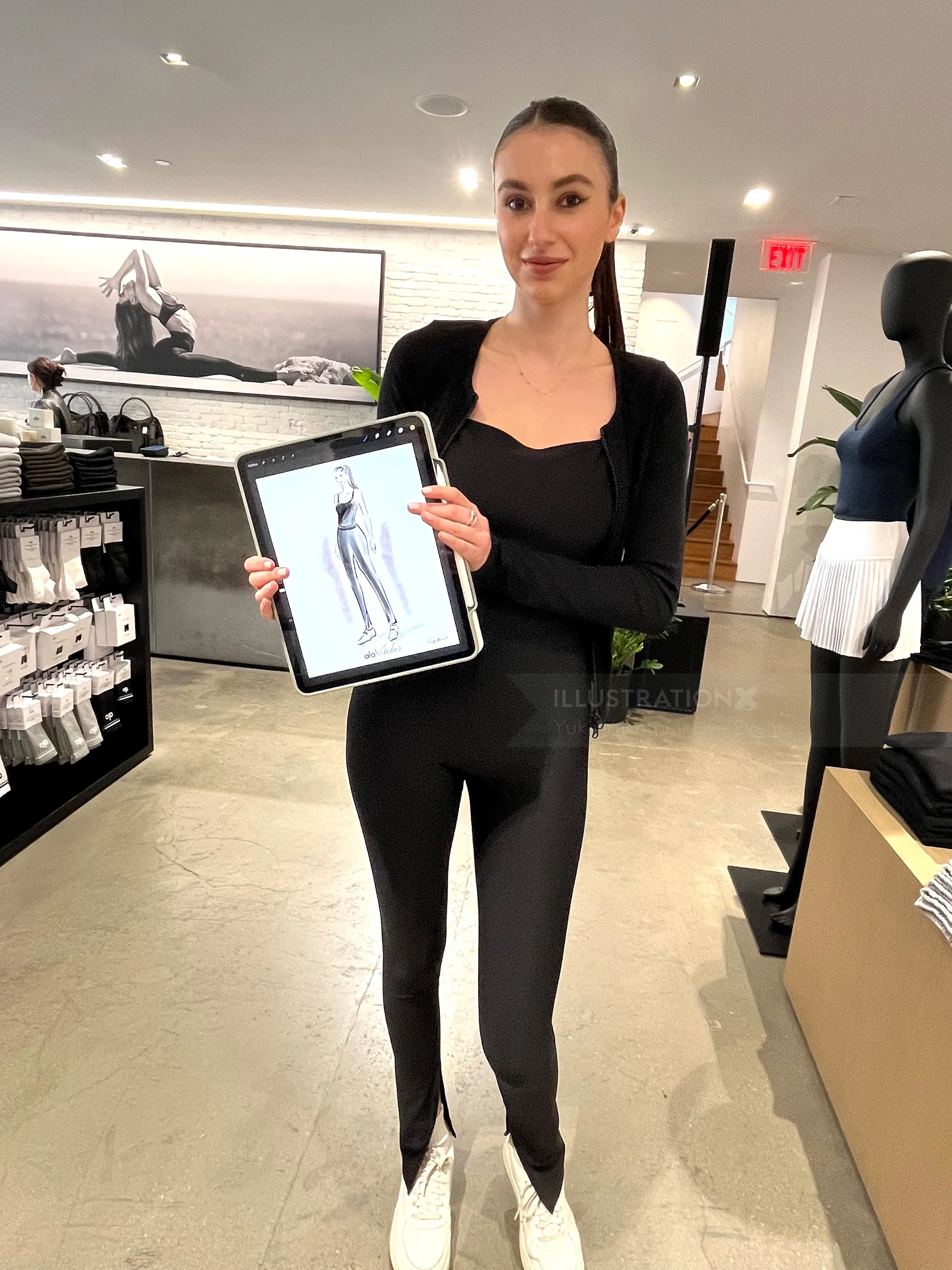 Woman in black outfit holding tablet showing workout pants