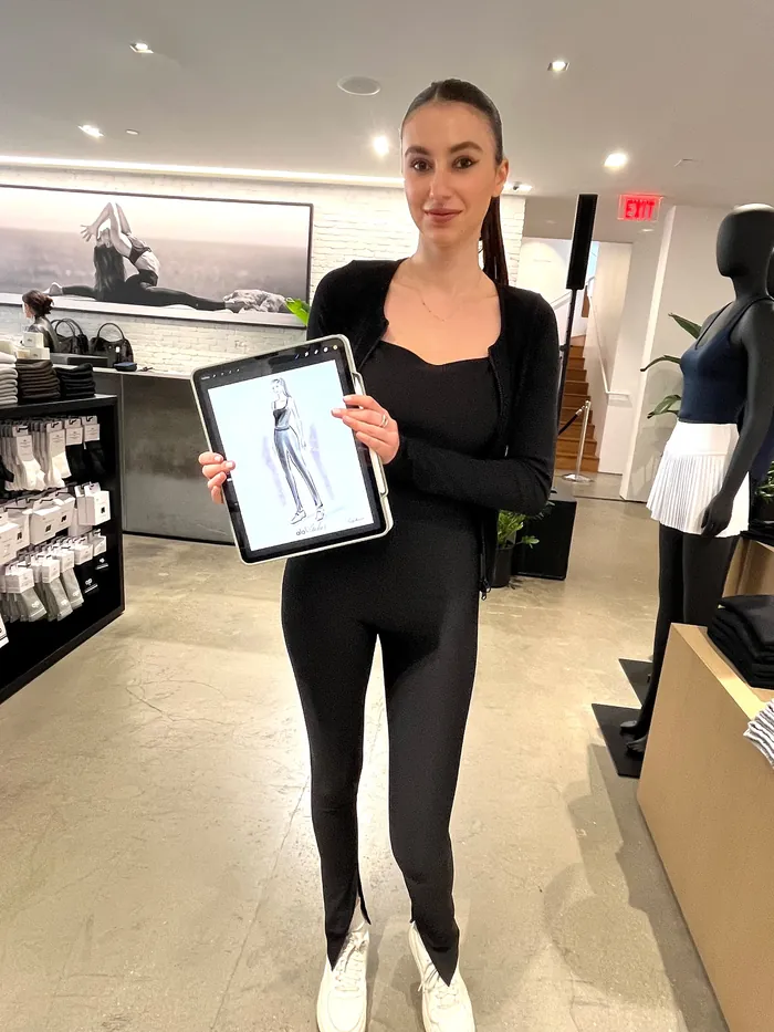 Woman in black outfit holding tablet showing workout pants