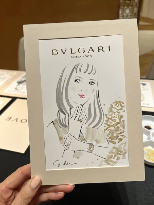 Hand holding Bulgari event card with elegant woman illustration