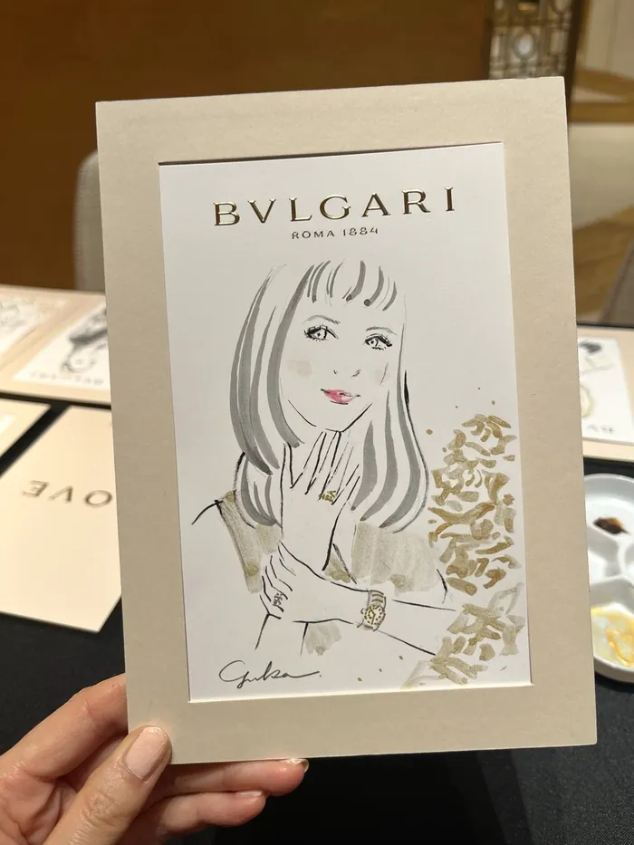 Hand holding Bulgari event card with elegant woman illustration