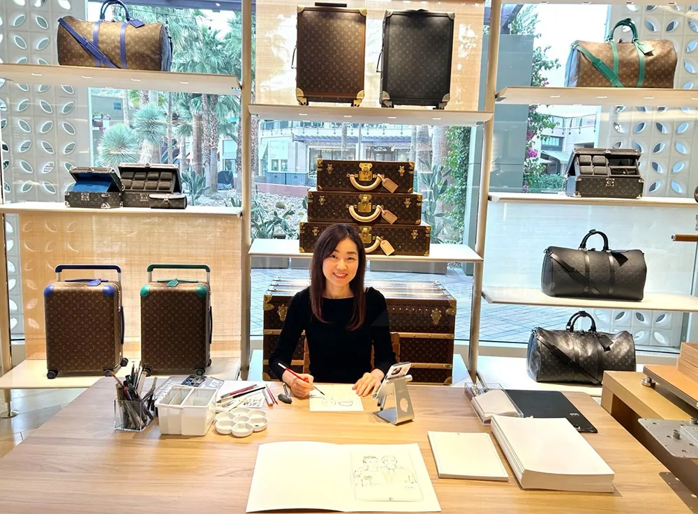Woman at desk during Louis Vuitton live event with luxury bags