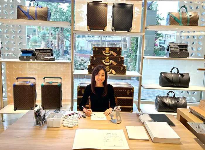 Woman at desk during Louis Vuitton live event with luxury bags