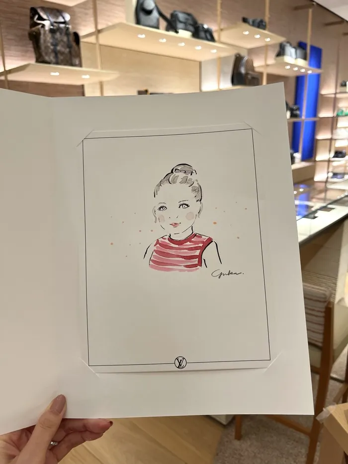 Hand holding sketch of a girl in a Louis Vuitton store