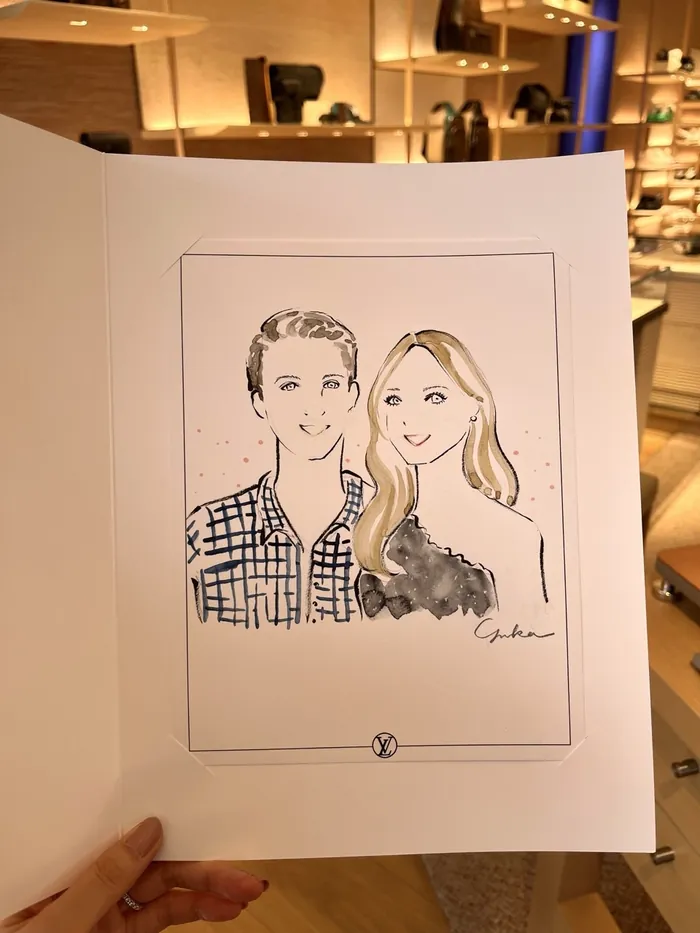 Hand holding sketch of smiling couple at Louis Vuitton event