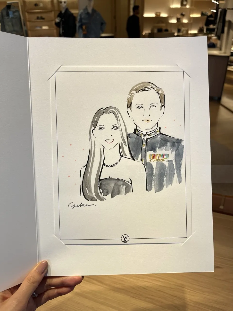 Hand holding a black and white caricature of a man and woman
