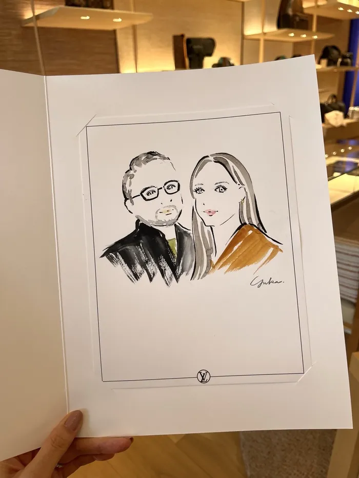 Hand holding a sketch of a man and woman in a boutique