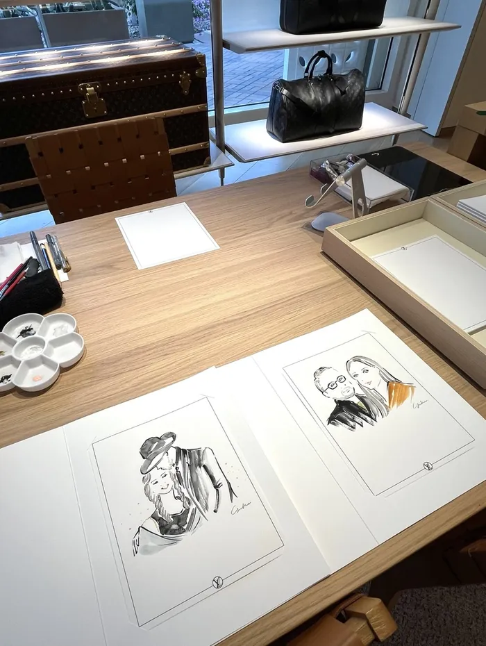 Sketches of fashion figures on a wooden table at Louis Vuitton event