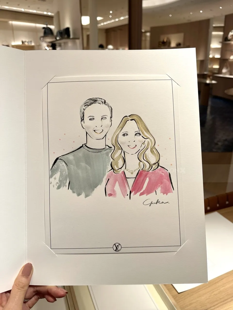 Hand holding a sketch of a smiling man and woman