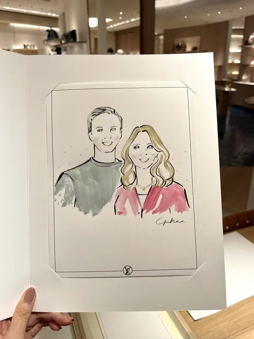 Hand holding a sketch of a smiling man and woman