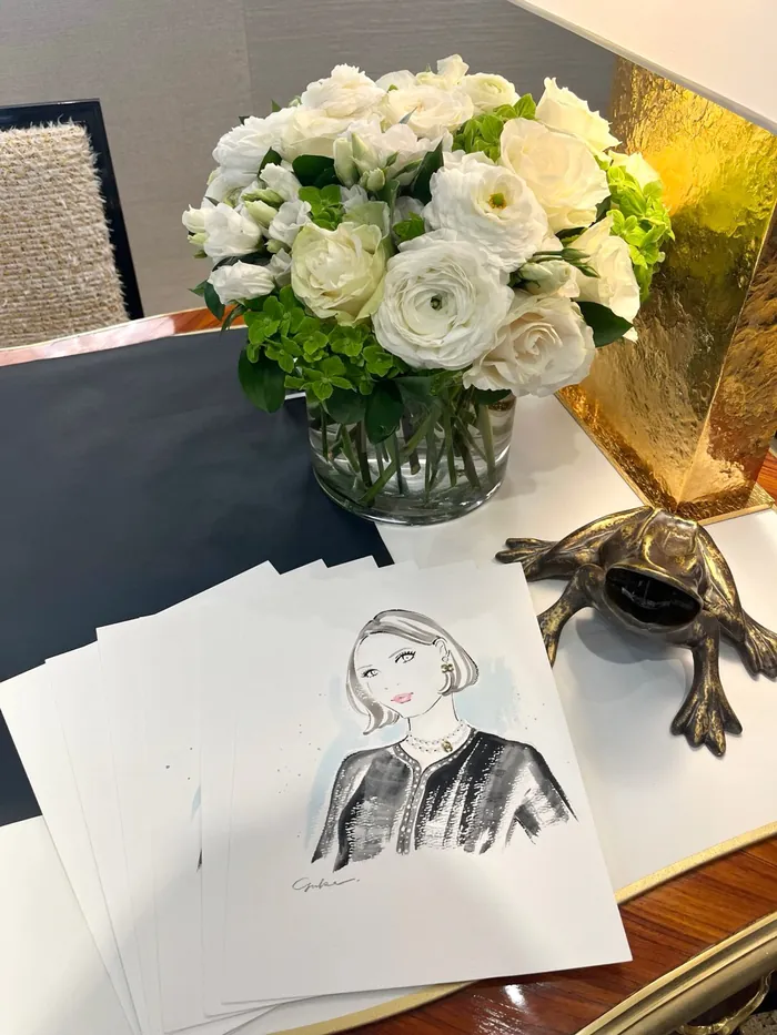 White floral bouquet next to fashion illustration sketches and a decorative frog