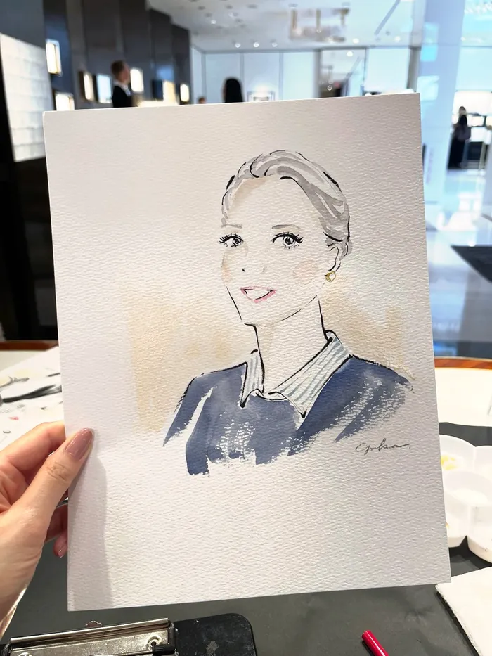 Hand holding watercolor portrait of a woman at an indoor event