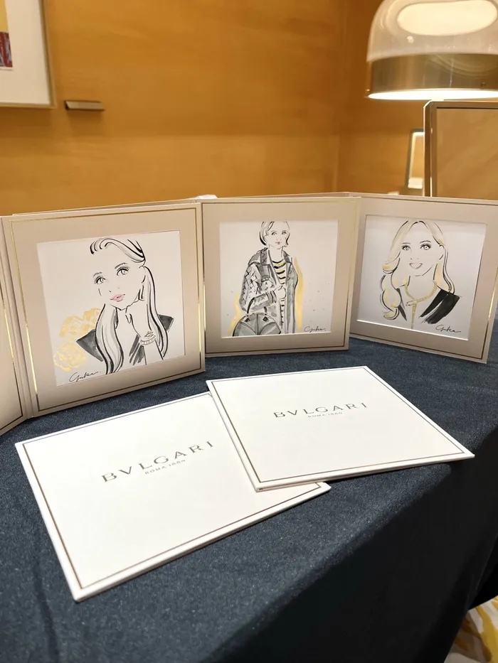 Illustrations of women in fashion with Bulgari branded cards on table