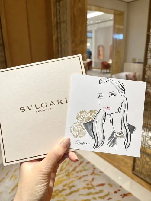 Hand holding Bulgari box and illustrated card in luxury interior