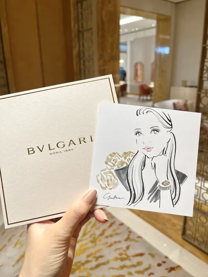 Hand holding Bulgari box and illustrated card in luxury interior