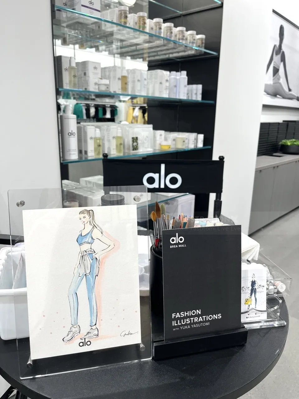 Alo branded event table with fashion illustrations and skincare products