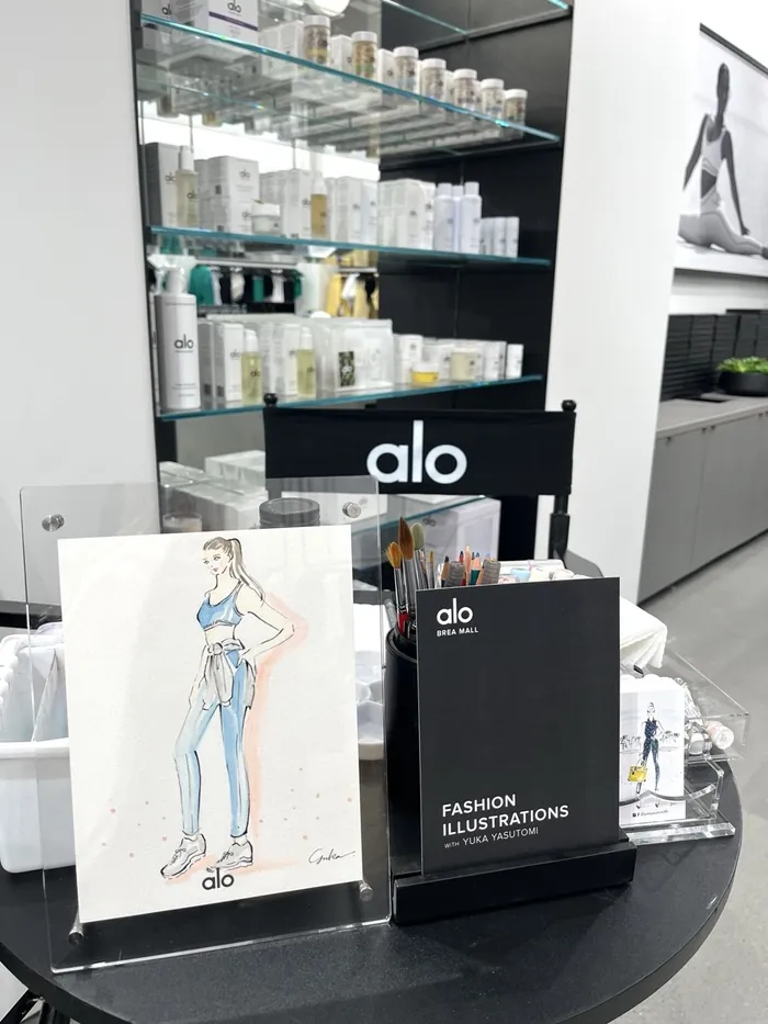 Alo branded event table with fashion illustrations and skincare products