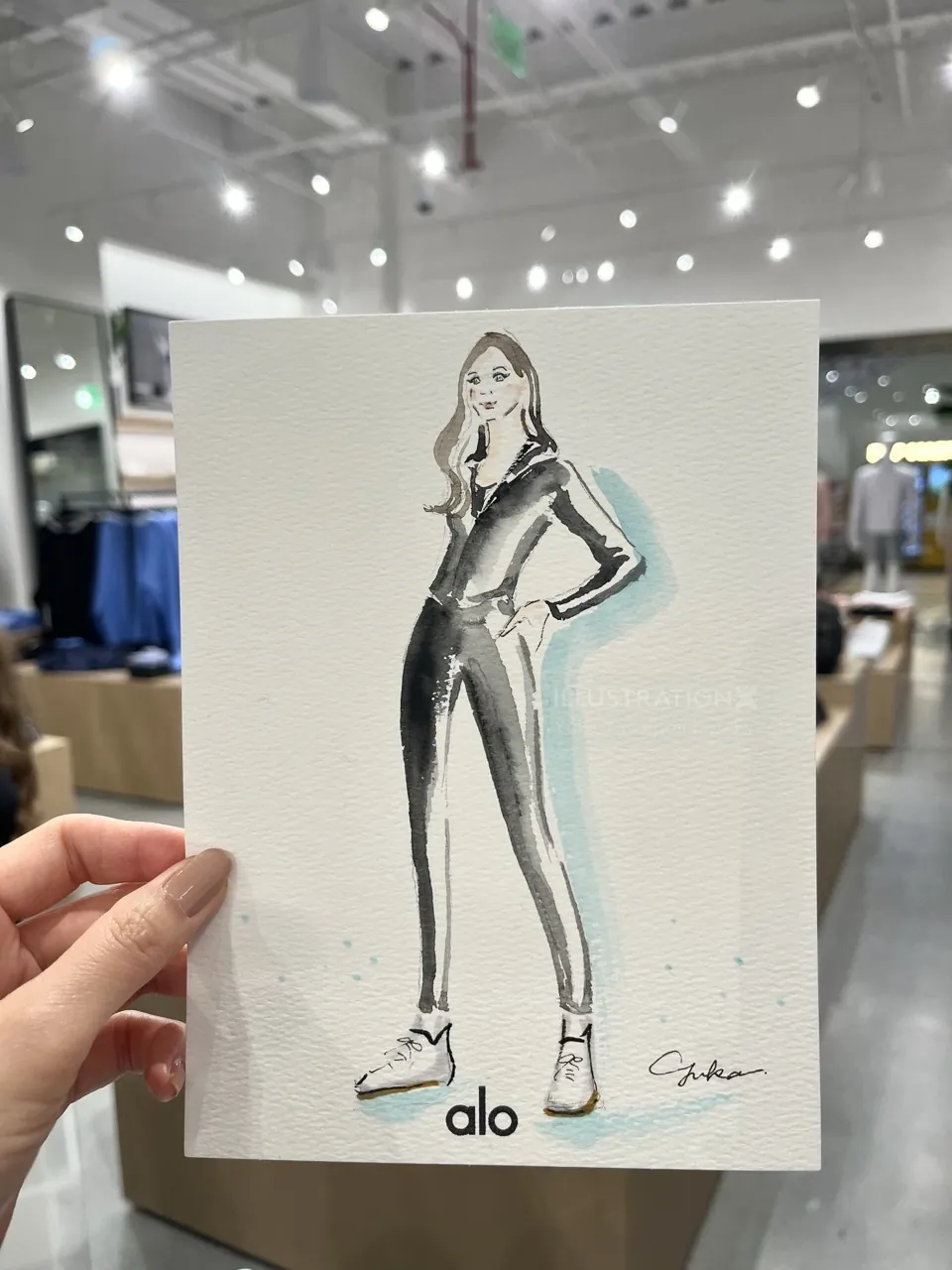 Hand holding a fashion illustration of a woman in a jumpsuit