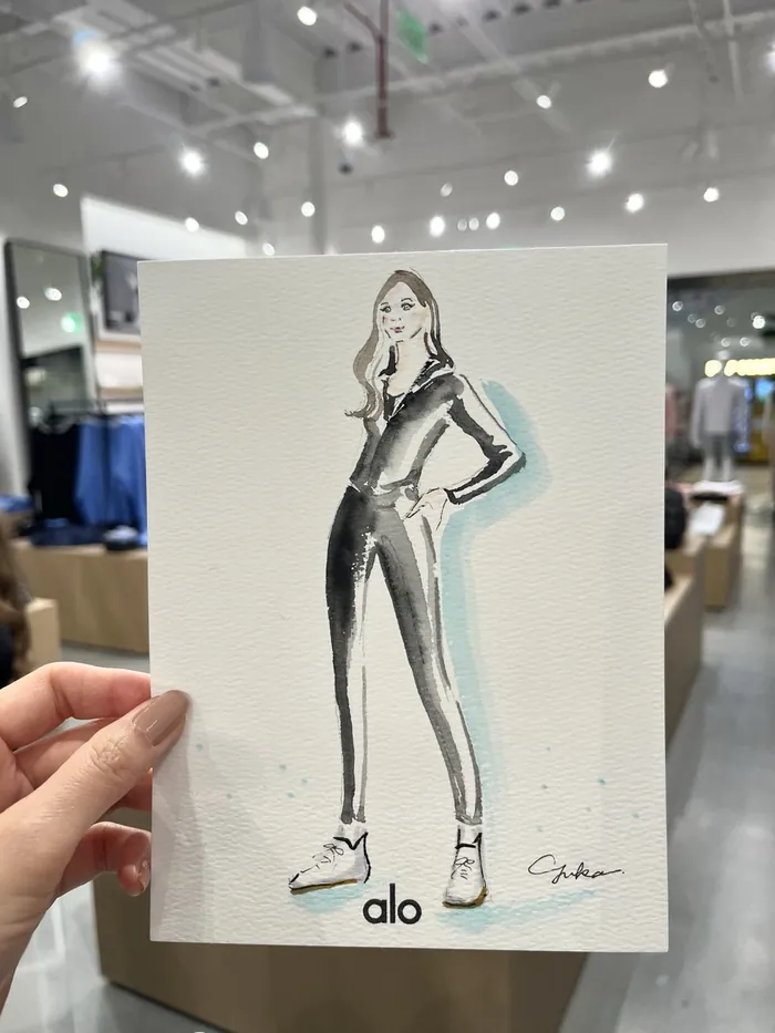 Hand holding a fashion illustration of a woman in a jumpsuit