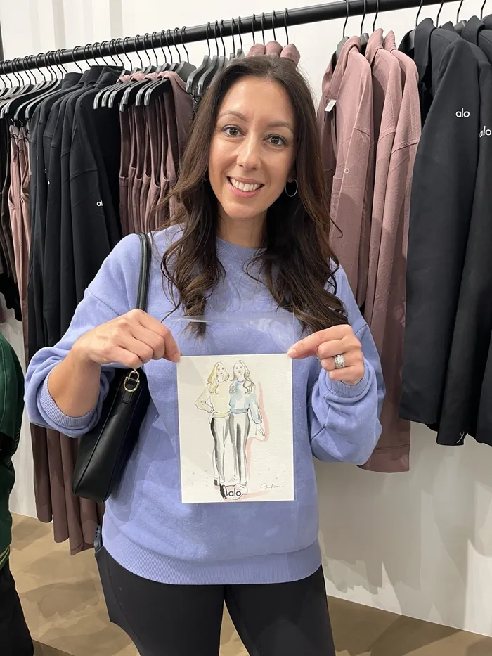 Woman holding fashion sketch at Alo Live Event with clothing racks