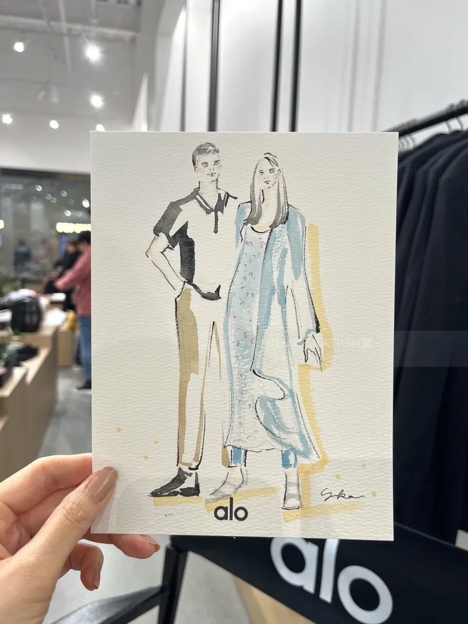 Hand holding fashion illustration of male and female models in casual clothes