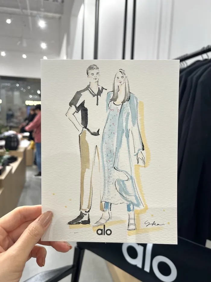 Hand holding fashion illustration of male and female models in casual clothes