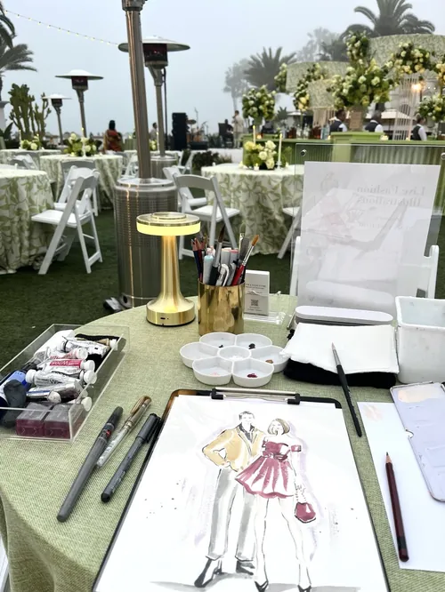Table with art supplies and fashion illustration at outdoor event