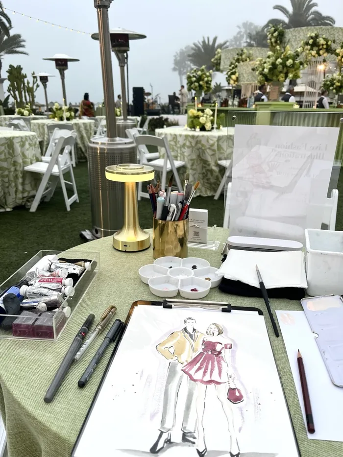 Table with art supplies and fashion illustration at outdoor event