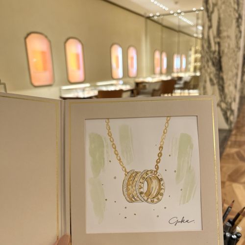 Mão segurando esboço de joias de anéis de ouro Bulgari dentro de livro de exposição