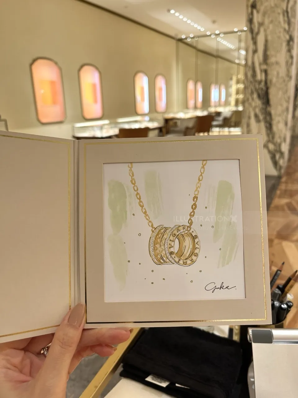 Hand holding jewelry sketch of gold Bulgari rings inside display book