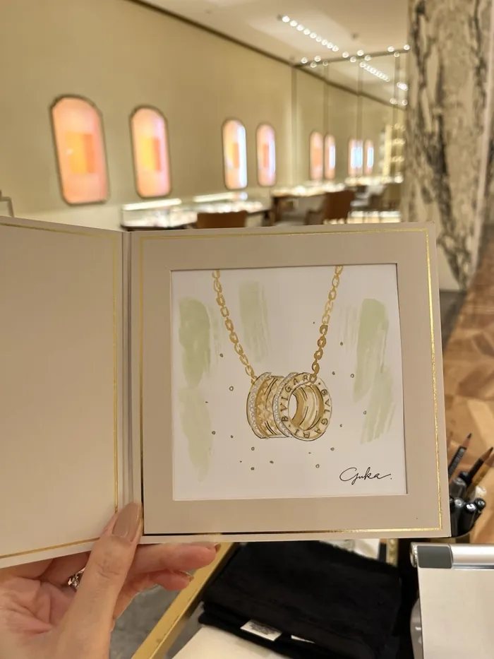 Hand holding jewelry sketch of gold Bulgari rings inside display book