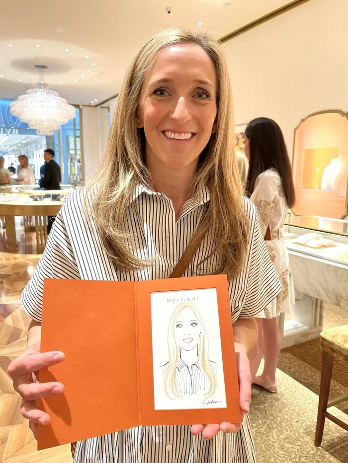 Smiling woman holding a caricature drawing at a Bulgari event