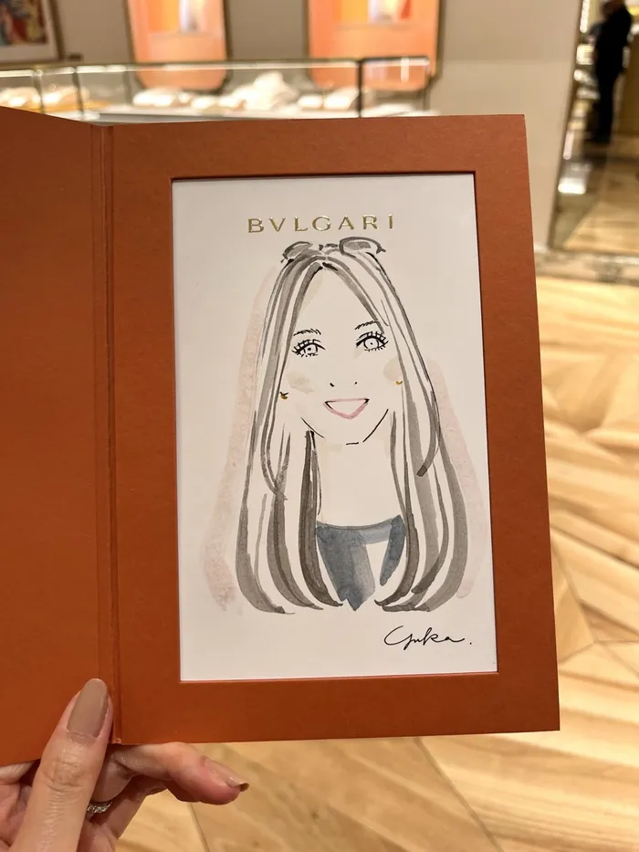 Hand holding a framed Bulgari caricature portrait inside boutique