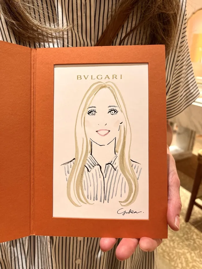 Hand holding a sketch portrait of a blonde woman in striped shirt