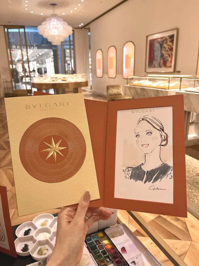 Hand holding a framed illustrated portrait in elegant jewelry store interior