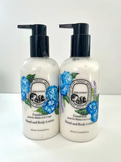 Two diptyque hand and body lotion bottles with blue floral design