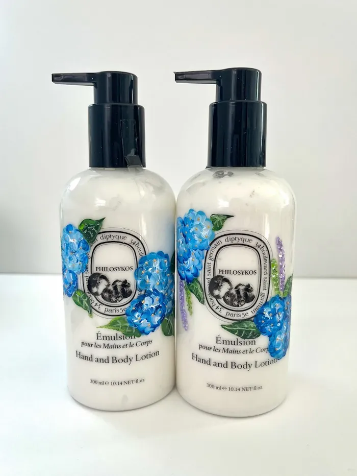 Two diptyque hand and body lotion bottles with blue floral design