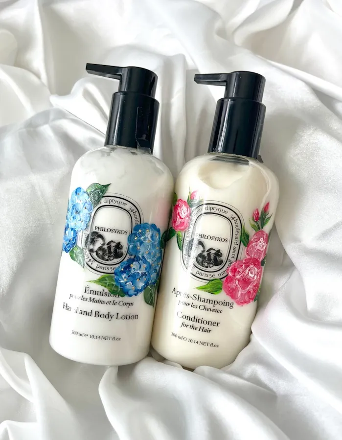 Two Diptyque lotion and shampoo bottles with floral designs