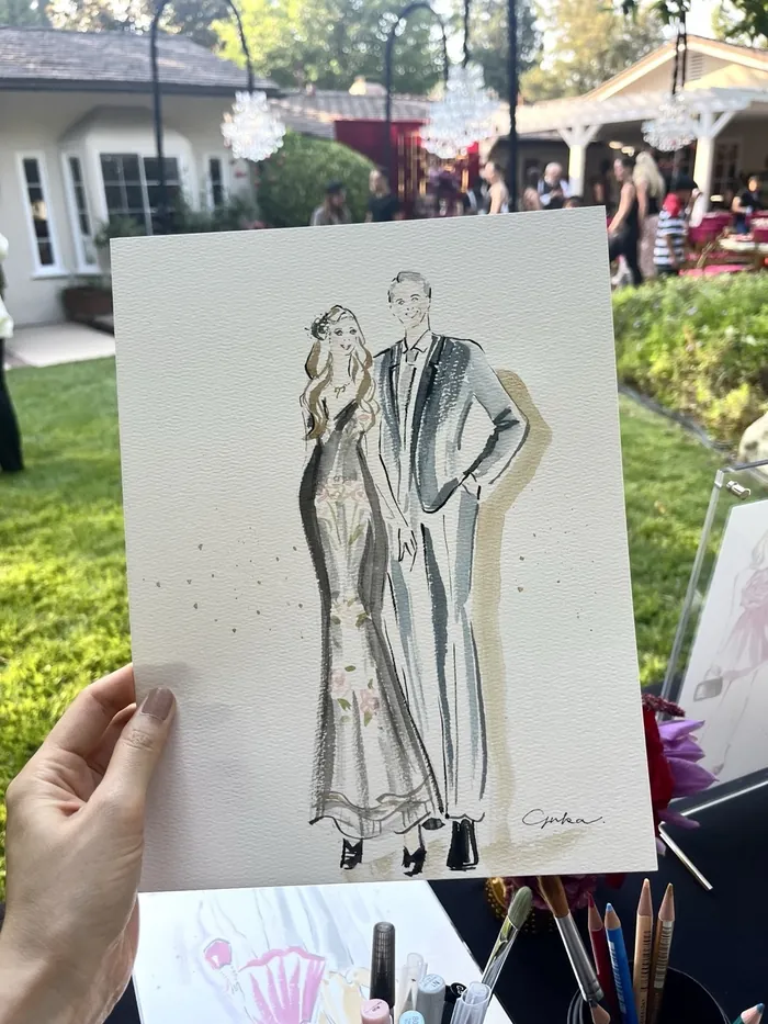 Hand holding an elegant fashion illustration at an outdoor event